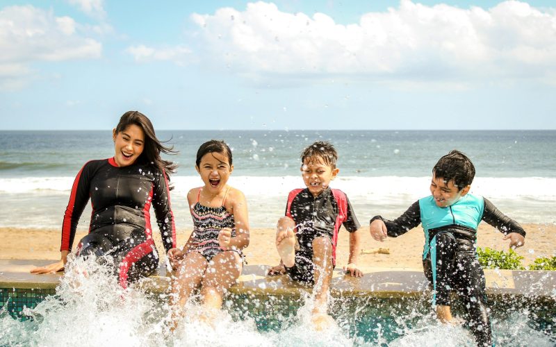 A family having fun splashing water near the seashore on a sunny day in Bali, Indonesia.