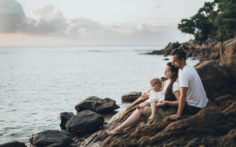 A serene family moment by the seaside, capturing love and relaxation at sunset.