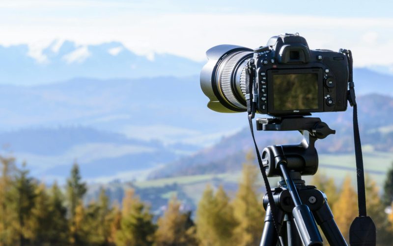DSLR camera on tripod capturing a stunning mountain view on a clear day.